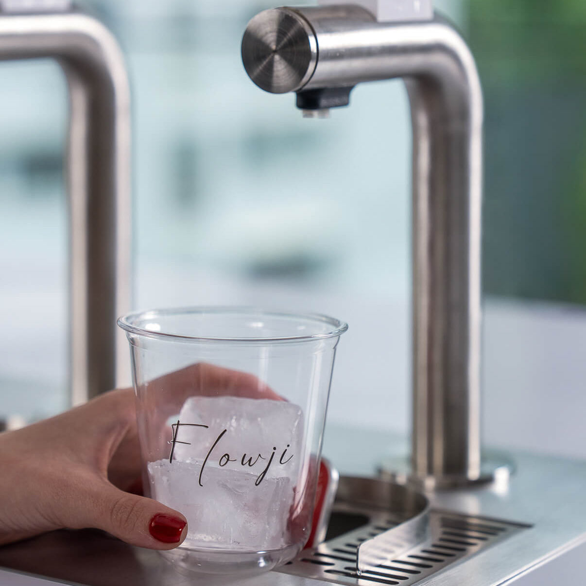Guest placing a Flowji cup beneath the dispensing tap to start preparing a freshly made beverage.